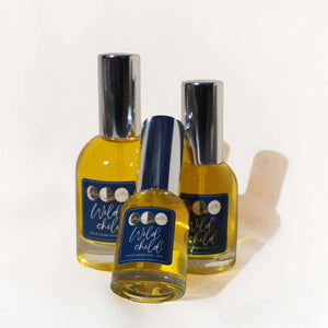 Three bottles of 'Wild Child' perfume on a white background