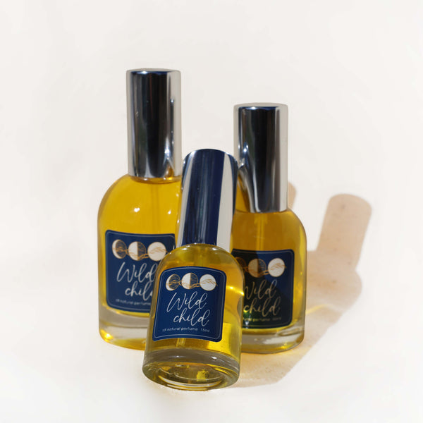 Three bottles of 'Wild Child' perfume on a white background