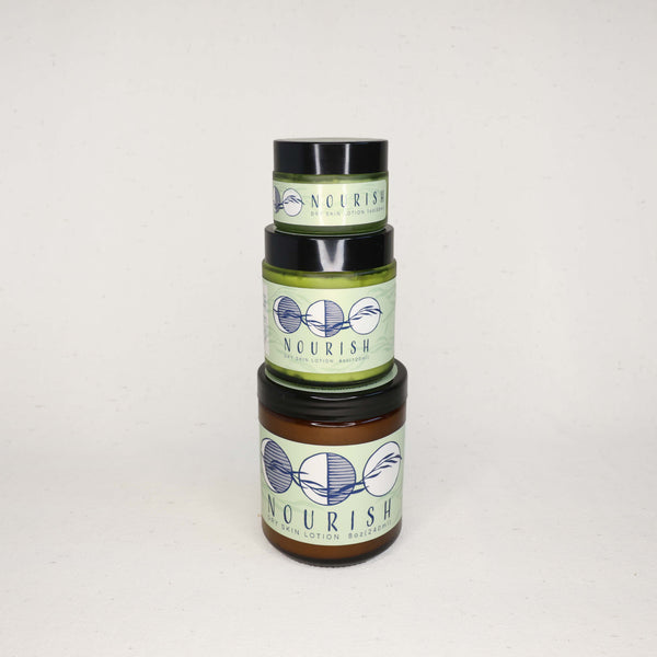 Three stacked jars of 'Nourish' dry skin lotion on a white background