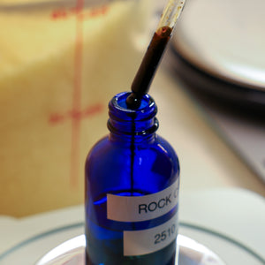 A cobalt blue glass dropper bottle with a white label 