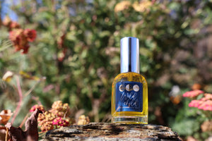 Bottle of 'Wild Child' perfume on a rock with a natural background