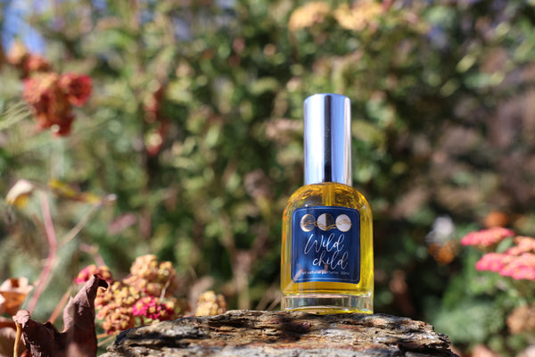 Bottle of 'Wild Child' perfume on a rock with a natural background