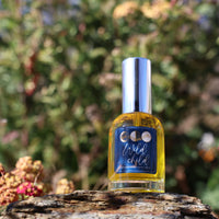 Bottle of 'Wild Child' perfume on a rock with a natural background